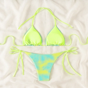 Detailed flat lay of neon yellow bikini top and tie-dye blue bottoms on white fabric