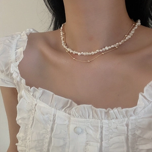 Close-up of double-layered Baroque pearl necklace with golden chain on model's neck