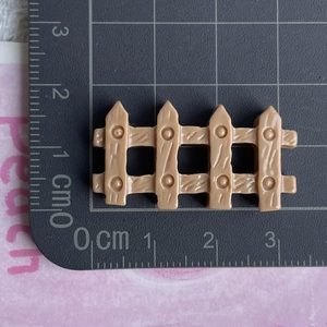 Detailed close-up of a miniature beige resin fence accessory measured on a cutting mat