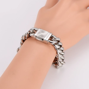 Close-up of silver Cuban link bracelet with engraved square clasp on male wrist