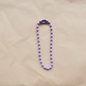 Close-up of a 2.4mm purple metal bead chain with connector on textured paper background
