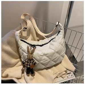 Detail of quilted creamy white hobo bag with a cute brown bunny charm on knit sweater