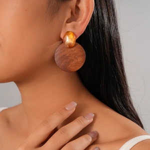 Détail de la boucle d'oreille géométrique en résine ambre et bois marron sur modèle