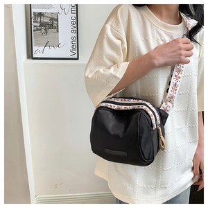 Detail of waterproof nylon crossbody bag with ethnic print strap worn by model