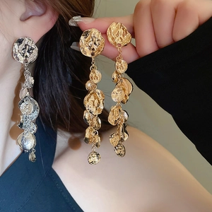 Détail de boucles d'oreilles à pompons métalliques irréguliers avec texture martelée