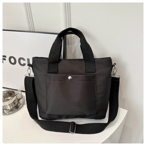 Detalle de bolso tote de nailon negro con correa ajustable y bolsillo con broche