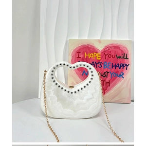 Detail of white heart-shaped acrylic handbag with wave texture and rhinestone handle