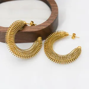Detailed view of large gold-plated C-shaped earrings with unique spring coil texture