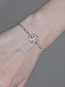 Nahaufnahme eines silbernen Blumenarmbands mit Perle, getragen am Handgelenk