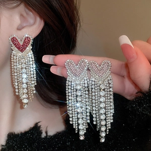 Detail of red heart rhinestone fringe earrings with shimmering silver tassels on model