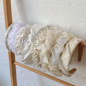 Detail view of pearl, silk bow, and lace headbands displayed on a wooden stand