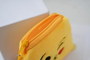 Detailed macro view of yellow plush coin purse showing the nylon zipper and soft fabric