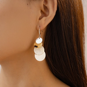 Close-up of model wearing bohemian geometric acrylic drop earrings with amber and pearl beads