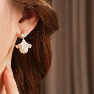 Gros plan de boucles d'oreilles ginkgo argentées avec perles blanches et zircons brillants