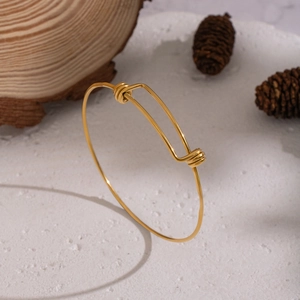 Detail of adjustable 18K gold plated stainless steel wire bracelet on wooden stand
