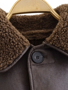 Detail of deep brown faux leather jacket with plush faux fur collar and black buttons