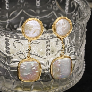 Baroque natural pearl drop earrings with gold wire wrap on vintage glass background