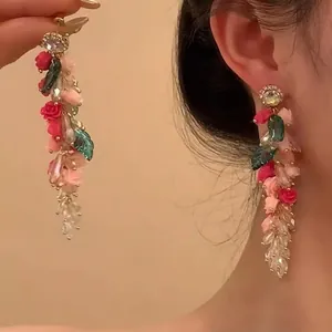 Détail de boucles d'oreilles fleurs avec roses en velours rose et perles de cristal