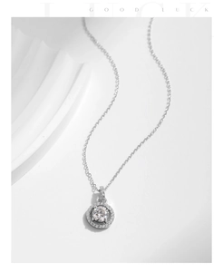 Close-up of S925 silver round moissanite pendant on white elegant gypsum surface