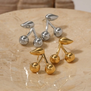 Minimalist cherry stud earrings in gold and silver finish on a textured stone tray