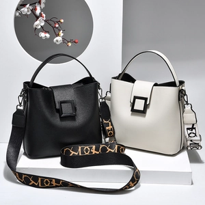 Minimalist black and white leather bucket bags with wide patterned straps on clean background