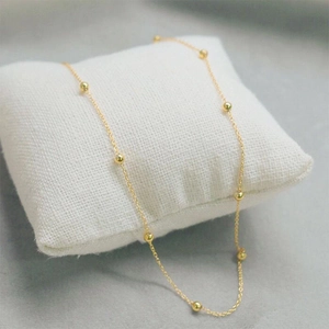 Elegant gold bead chain necklace for women made of durable titanium steel on white fabric