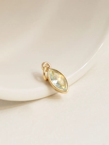 Macro detail of 18K gold-plated oval pendant with light blue marquise-cut zircon gemstone