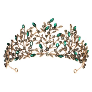 Detail of a vintage golden baroque crown with green rhinestones and leaf motifs