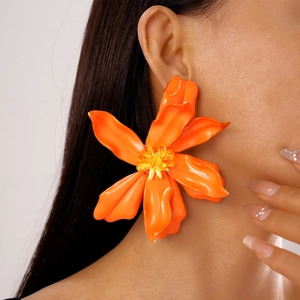Close-up of a large orange acrylic flower earring with beaded center on a female model