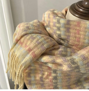 Detailed macro view of colorful plaid knit scarf with yellow base and fringe trim
