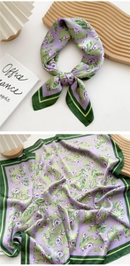 Detail of green and purple floral silk scarf with lilac patterns on a wavy wooden tray