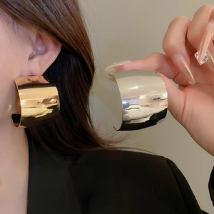 Macro shot of large polished C-shaped hoop earrings in gold and silver finishes