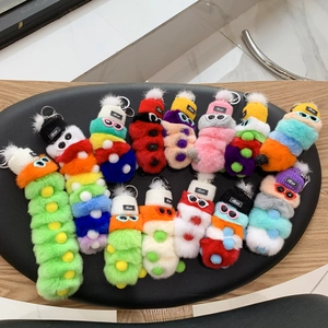 Close-up of fluffy caterpillar plush keychain with knitted hats and small goggles