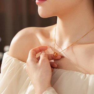 Gold plated waist cylinder necklace with red zircons shown on female model neck