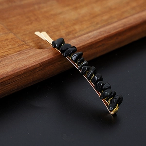 Detail view of gold metal hair clip featuring polished natural black crystal stones