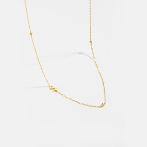 Detail of gold letter S necklace featuring a polished finish and three sparkling zircon accents