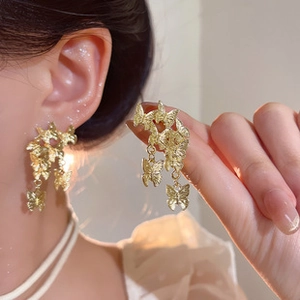Detailed close-up of glossy gold bow pendant earrings featuring elegant tassel design