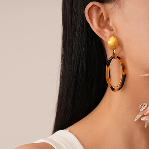 Close-up of leopard resin oval earrings with gold studs worn by a model in profile