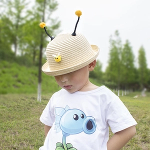Close-up of kids straw sun hat with cute yellow pom-poms and small bee decorative detail