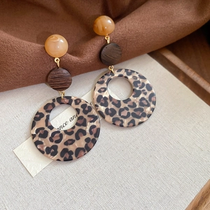 Detailed view of leopard print acrylic drop earrings with wooden and amber resin beads