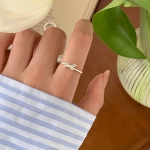 Minimalist silver bow ring worn by a model in a lifestyle setting with natural lighting