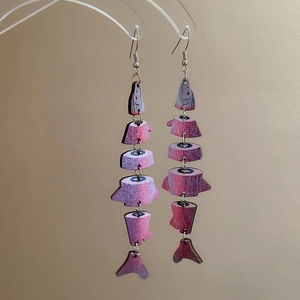 Macro shot of tiered wooden fish pendant earrings in pink-purple with ethnic fringe style