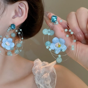 Detail of light blue fabric flower earrings with emerald-cut blue crystal and beads