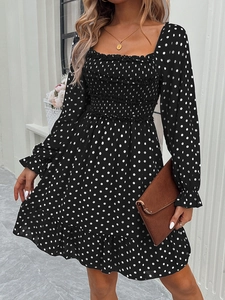 Detail of square neckline and polka dot pattern on a black long sleeve mini dress