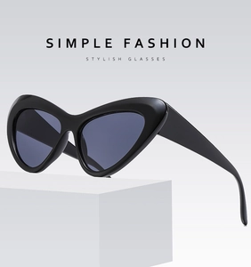Close-up of black cat-eye sunglasses on a white pedestal showing glossy frame finish