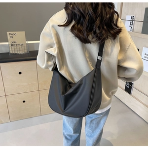 Modern black oversized hobo crossbody bag shown from a back perspective on a model