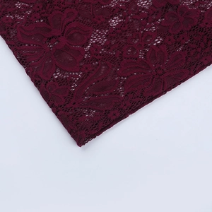 Close-up of wine red lace fabric with intricate floral crochet and scallop details