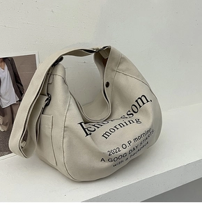 Détail du sac cabas en toile beige avec imprimé lettrage noir et bandoulière réglable