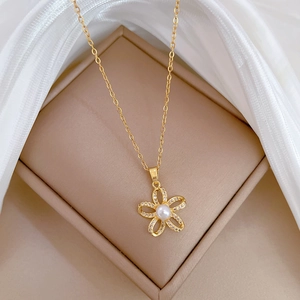 Macro shot of gold floral necklace with pearl center and diamond inlay in a gift box
