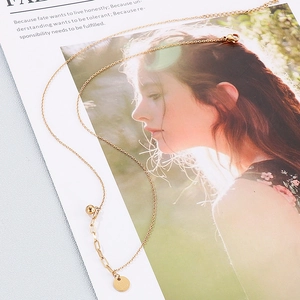 Detail of gold necklace with 'Good Luck' round pendant on a stylish fashion poster